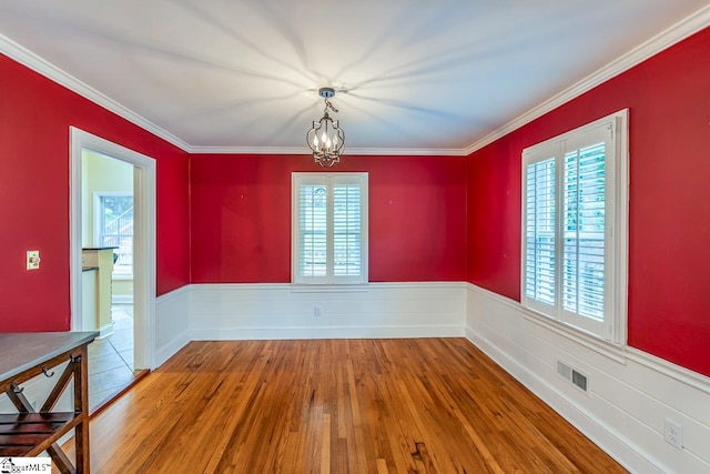 unfurnished dining area featuring ornamental molding, a notable chandelier, and hardwood / wood-style flooring