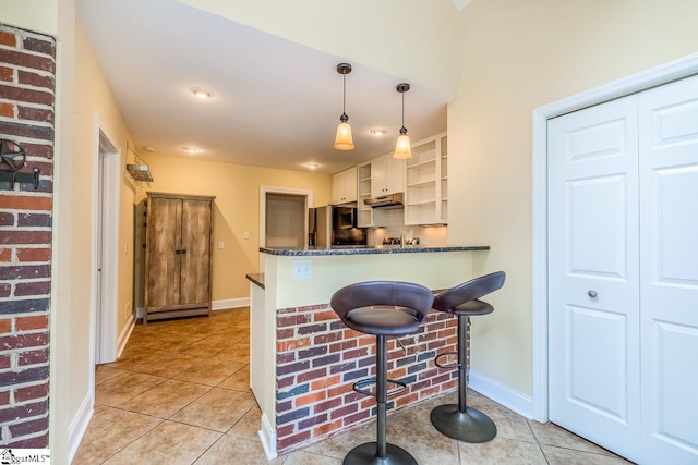 kitchen featuring light tile patterned flooring, dark stone counters, stainless steel fridge with ice dispenser, pendant lighting, and kitchen peninsula