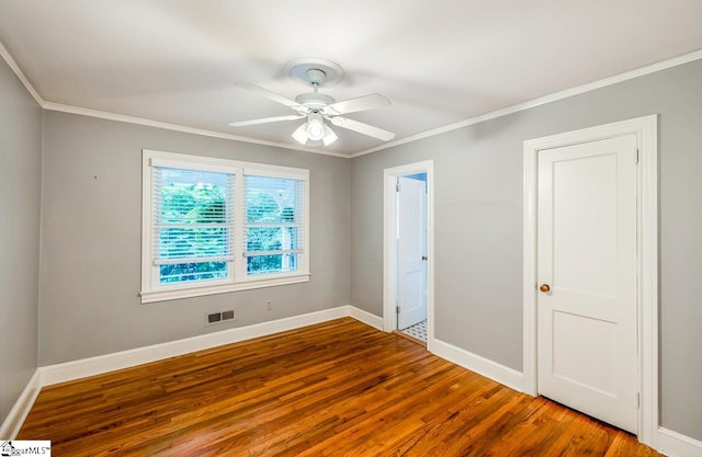 empty room featuring ornamental molding, wood-type flooring, and ceiling fan