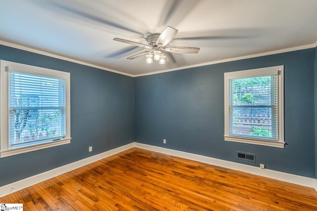 empty room featuring hardwood / wood-style floors, a wealth of natural light, and crown molding