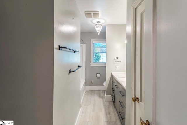 full bathroom with washtub / shower combination, a chandelier, vanity, and toilet