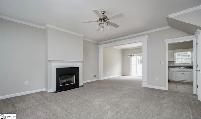 unfurnished living room featuring light colored carpet, crown molding, sink, and ceiling fan with notable chandelier