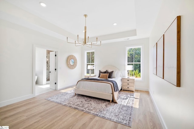 bedroom with a chandelier, light hardwood / wood-style floors, and ensuite bath