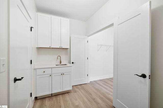 interior space with white cabinets, sink, and light hardwood / wood-style flooring