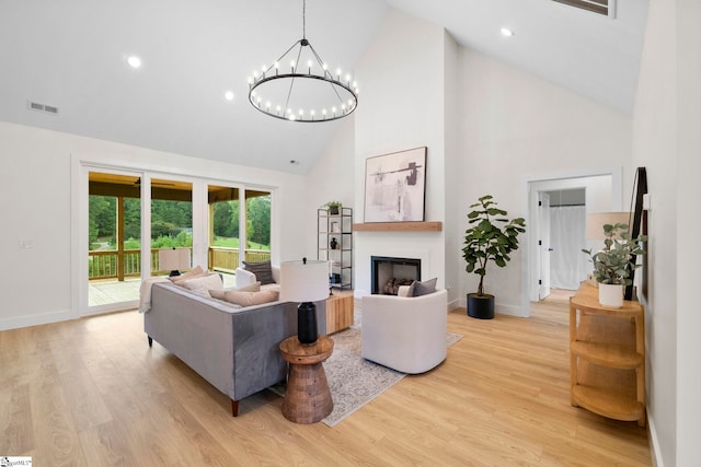 living room with light hardwood / wood-style floors, high vaulted ceiling, and a notable chandelier