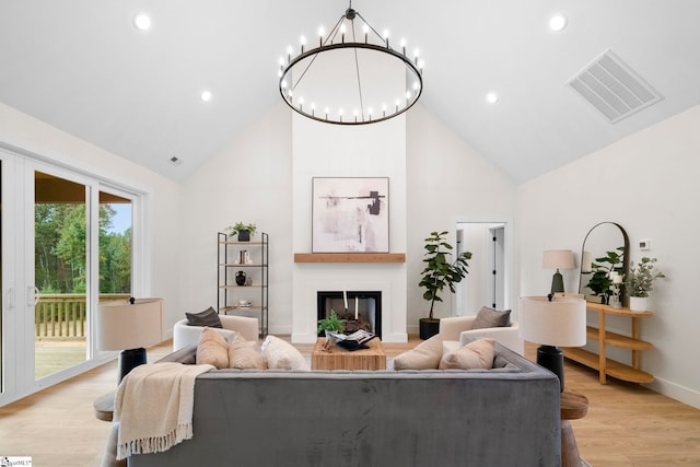 living room with high vaulted ceiling, light hardwood / wood-style flooring, and an inviting chandelier