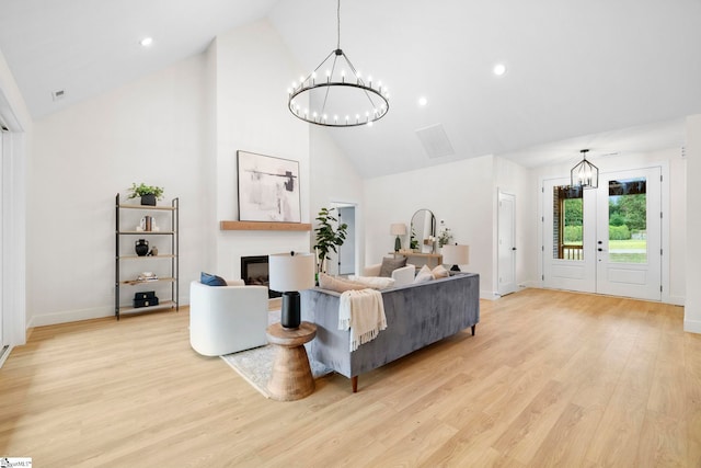 living room with light wood-type flooring, high vaulted ceiling, and a notable chandelier