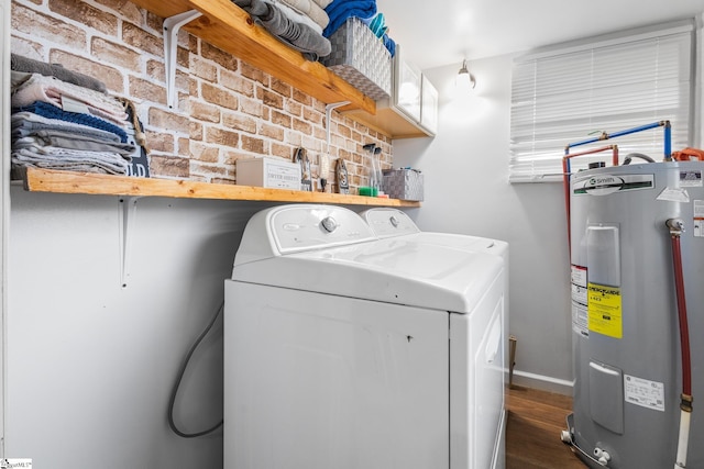 laundry room featuring electric water heater, separate washer and dryer, brick wall, and dark wood-type flooring