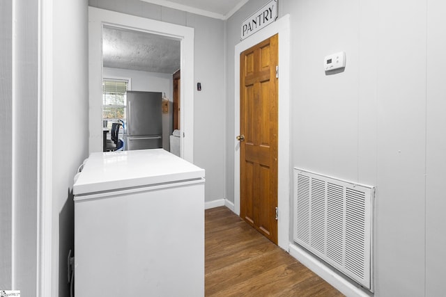 clothes washing area featuring hardwood / wood-style floors and crown molding