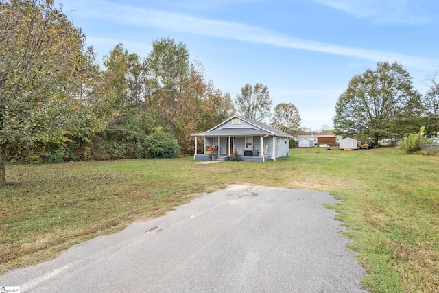 view of front of home featuring covered porch, a front yard, and a storage unit