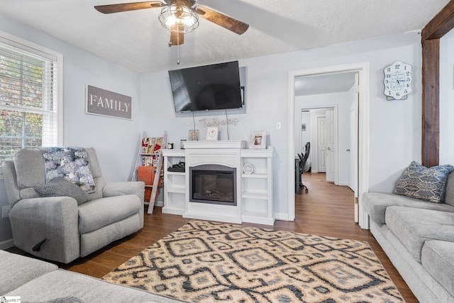 living room with a textured ceiling, dark hardwood / wood-style flooring, and ceiling fan