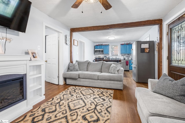 living room featuring a wealth of natural light, ceiling fan, a textured ceiling, and light hardwood / wood-style floors