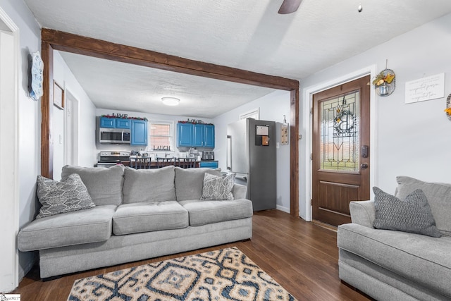 living room featuring dark wood-type flooring, a textured ceiling, and ceiling fan