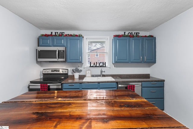 kitchen featuring blue cabinetry, appliances with stainless steel finishes, and a textured ceiling