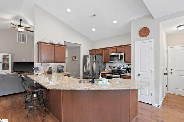 kitchen with lofted ceiling, kitchen peninsula, a breakfast bar area, dark hardwood / wood-style floors, and appliances with stainless steel finishes