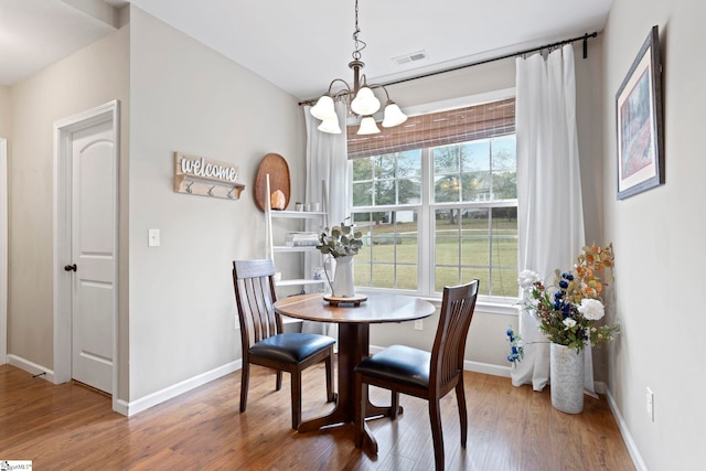 dining area featuring hardwood / wood-style floors, a healthy amount of sunlight, and a chandelier