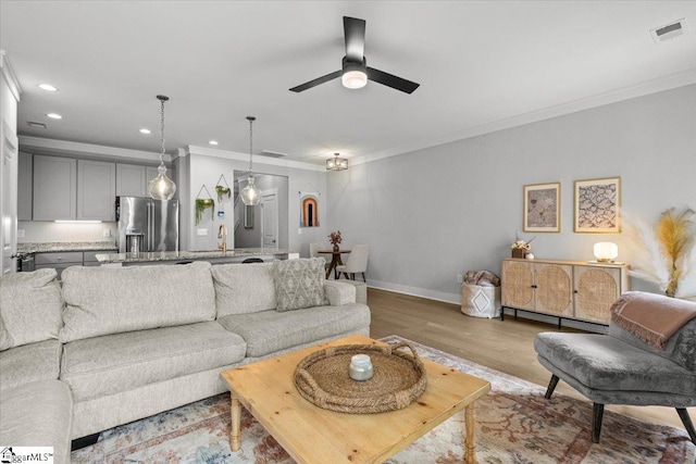 living room featuring light hardwood / wood-style floors, ceiling fan, and ornamental molding