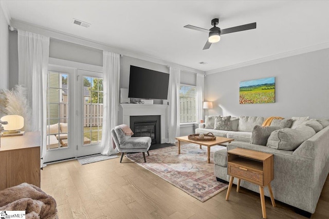 living room with light hardwood / wood-style floors, ceiling fan, and ornamental molding