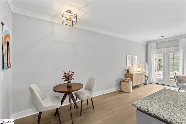 dining room with a chandelier, light wood-type flooring, and ornamental molding