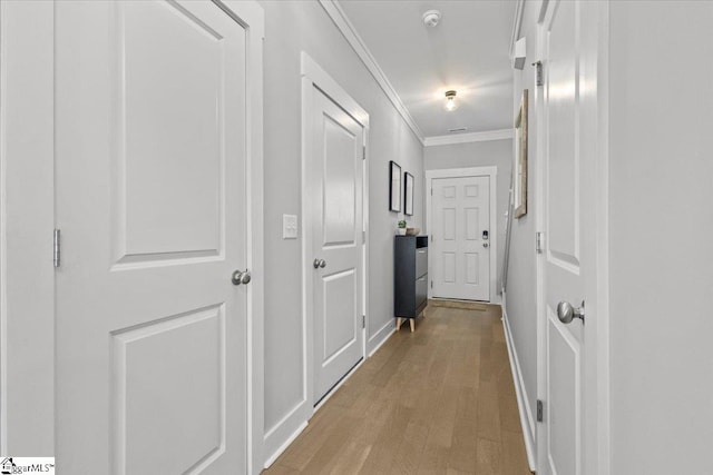 corridor featuring light wood-type flooring and crown molding