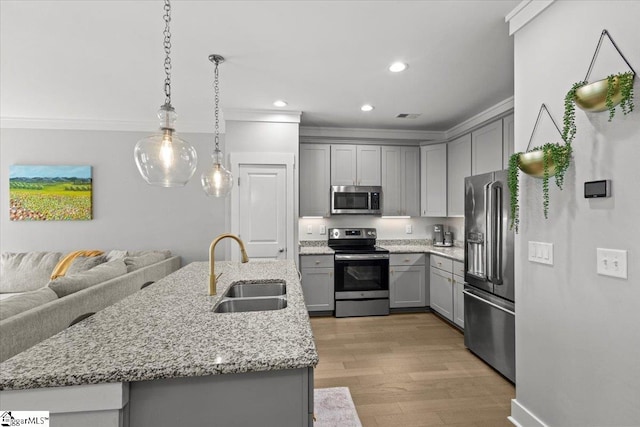 kitchen featuring stainless steel appliances, hanging light fixtures, sink, gray cabinets, and light hardwood / wood-style flooring