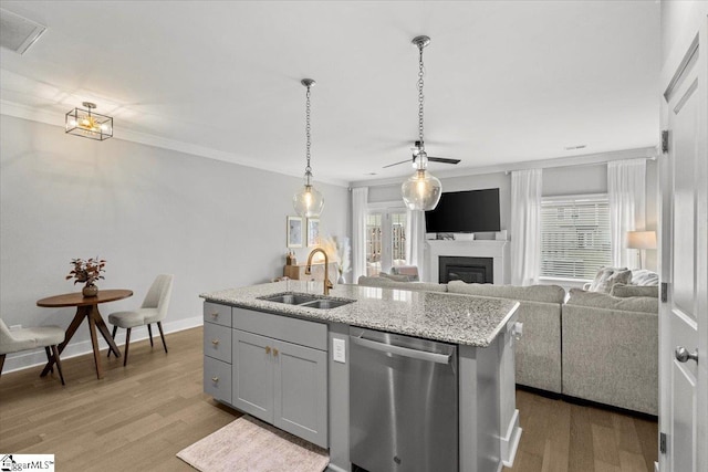 kitchen with dishwasher, a wealth of natural light, sink, an island with sink, and light wood-type flooring