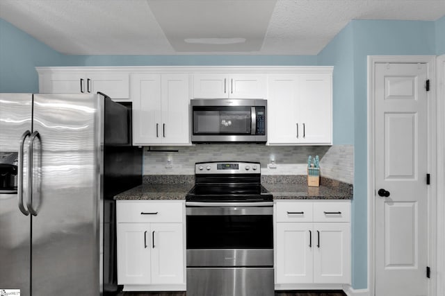 kitchen with dark stone counters, tasteful backsplash, white cabinetry, and stainless steel appliances