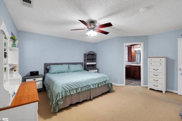 bedroom featuring connected bathroom, a textured ceiling, sink, light colored carpet, and ceiling fan