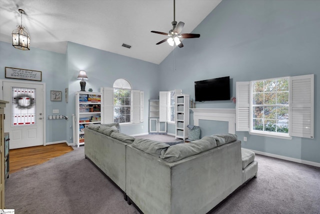 living room featuring high vaulted ceiling, ceiling fan with notable chandelier, and carpet floors