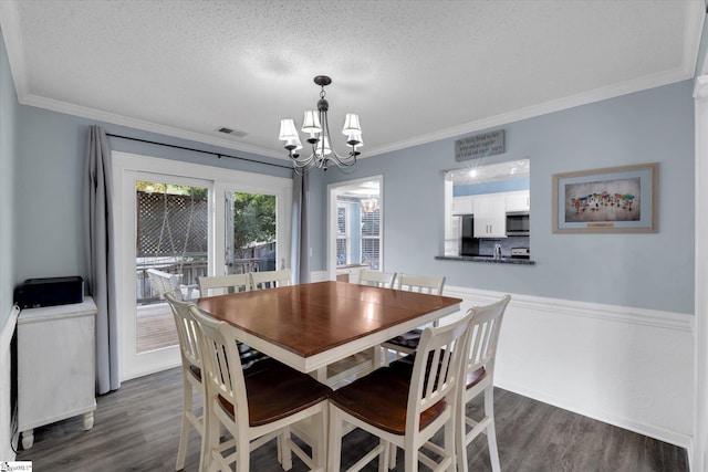 dining space with dark wood-type flooring, a chandelier, a textured ceiling, and crown molding