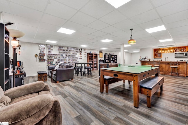 rec room featuring indoor bar, wood-type flooring, and a drop ceiling