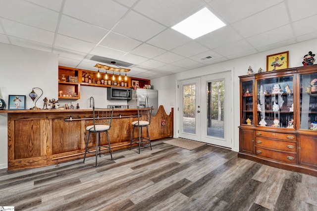 bar with stainless steel appliances, dark hardwood / wood-style floors, decorative light fixtures, a paneled ceiling, and french doors