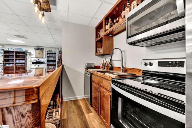 kitchen featuring a paneled ceiling, appliances with stainless steel finishes, light hardwood / wood-style floors, and sink