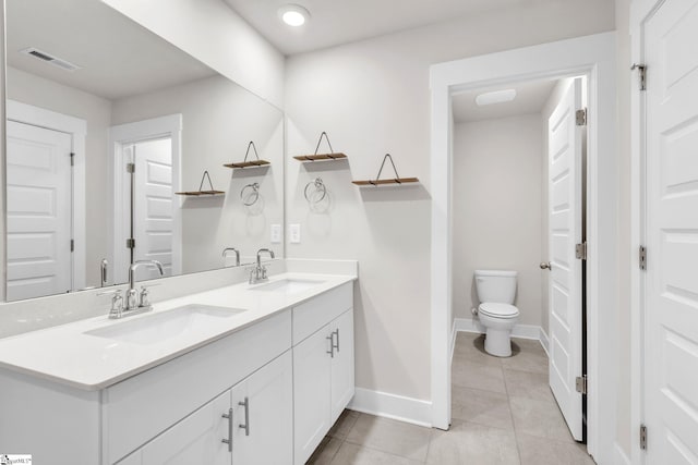 bathroom with toilet, vanity, and tile patterned flooring