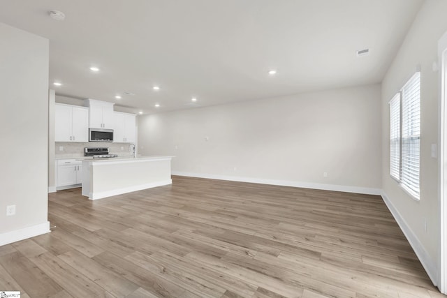 unfurnished living room featuring sink and light wood-type flooring