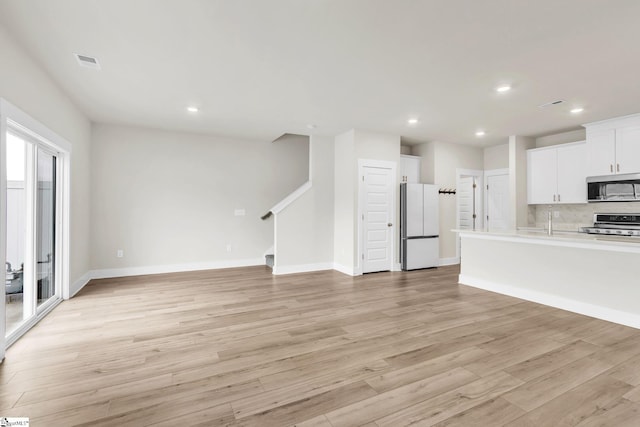 unfurnished living room featuring sink and light hardwood / wood-style floors