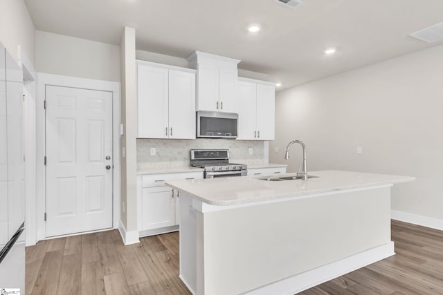 kitchen featuring light hardwood / wood-style floors, sink, a kitchen island with sink, white cabinetry, and appliances with stainless steel finishes