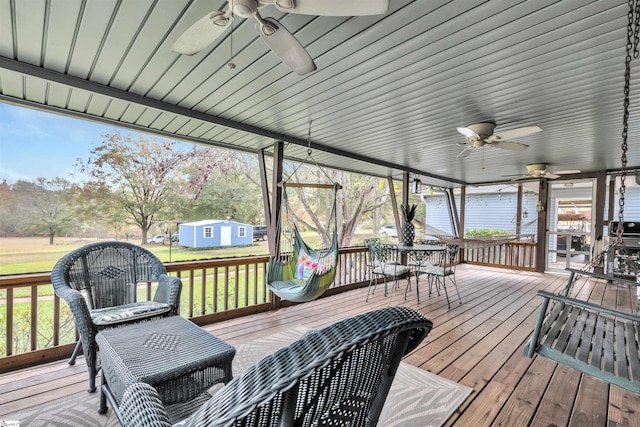 deck with a lawn, a shed, and ceiling fan