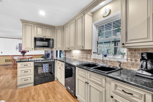 kitchen with black appliances, tasteful backsplash, cream cabinets, light wood-type flooring, and sink