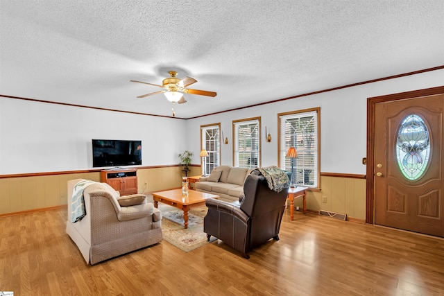 living room featuring ornamental molding, ceiling fan, a textured ceiling, and light hardwood / wood-style floors