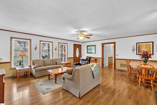 living room with ceiling fan, a textured ceiling, light hardwood / wood-style flooring, and crown molding