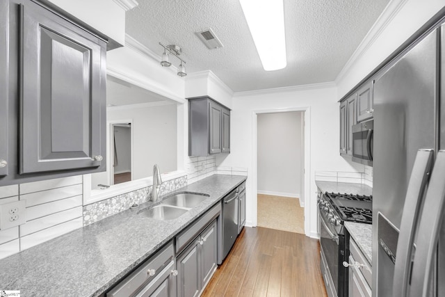 kitchen featuring dark hardwood / wood-style flooring, decorative backsplash, a textured ceiling, sink, and appliances with stainless steel finishes