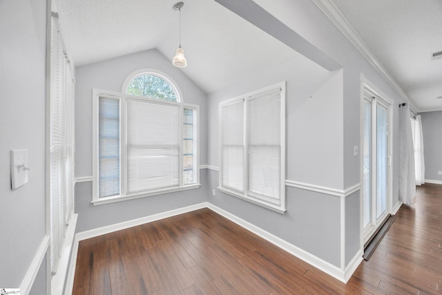 interior space featuring dark wood-type flooring, vaulted ceiling, and ornamental molding