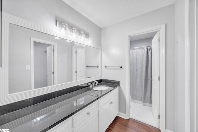 bathroom featuring a textured ceiling, curtained shower, vanity, and hardwood / wood-style flooring