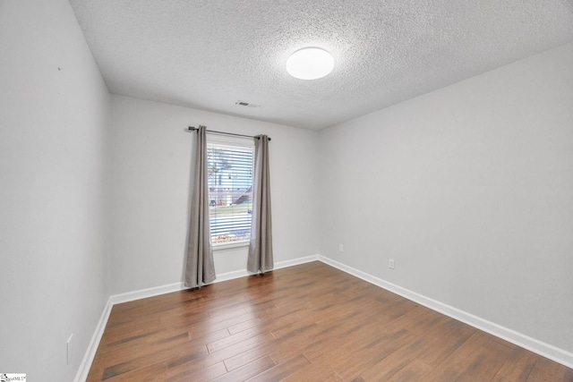 spare room featuring a textured ceiling and dark hardwood / wood-style floors