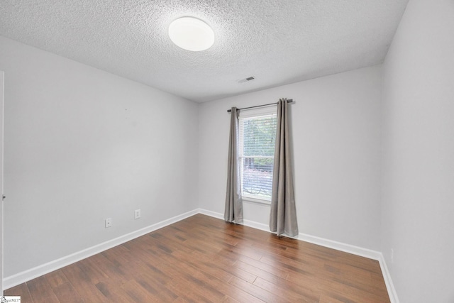 spare room featuring a textured ceiling and dark hardwood / wood-style flooring