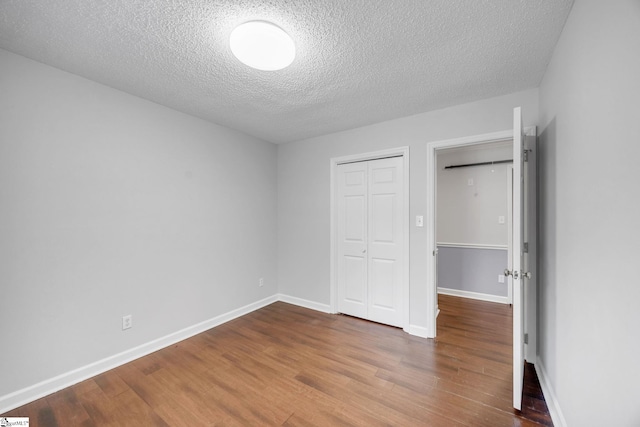 unfurnished bedroom with a closet, a textured ceiling, and hardwood / wood-style flooring