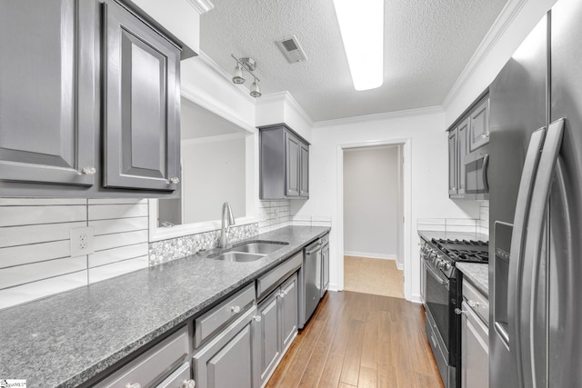 kitchen featuring crown molding, stainless steel appliances, a textured ceiling, sink, and hardwood / wood-style flooring