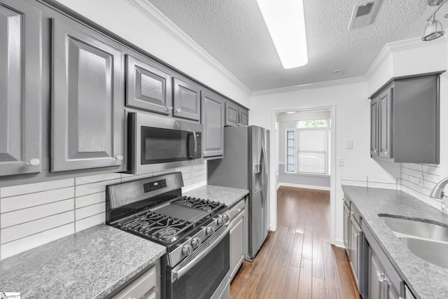 kitchen with a textured ceiling, decorative backsplash, stainless steel appliances, and dark hardwood / wood-style floors