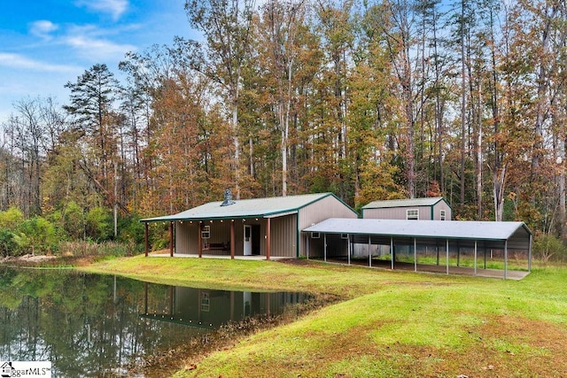 rear view of house with a water view, a yard, and a carport